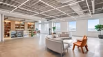 Unilever's company store with products on shelves, and a curved gray couch sitting area. The windows feature view of NYC skyline.